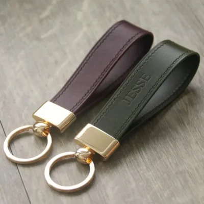 Brown and dark green leather keychain with gold-colored metal head and key ring