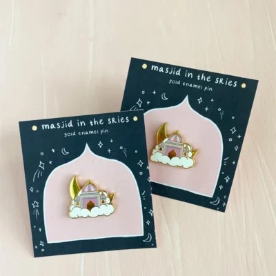 Two enamel pins featuring a mosque floating on clouds with a crescent moon, titled "Masjid in the Skies."