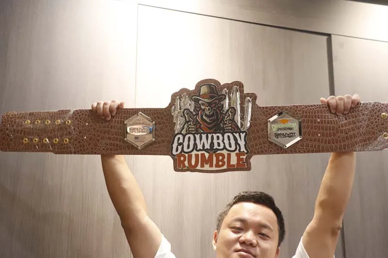 A man proudly displays a belt featuring a cowboy design, showcasing a blend of style and Western culture.