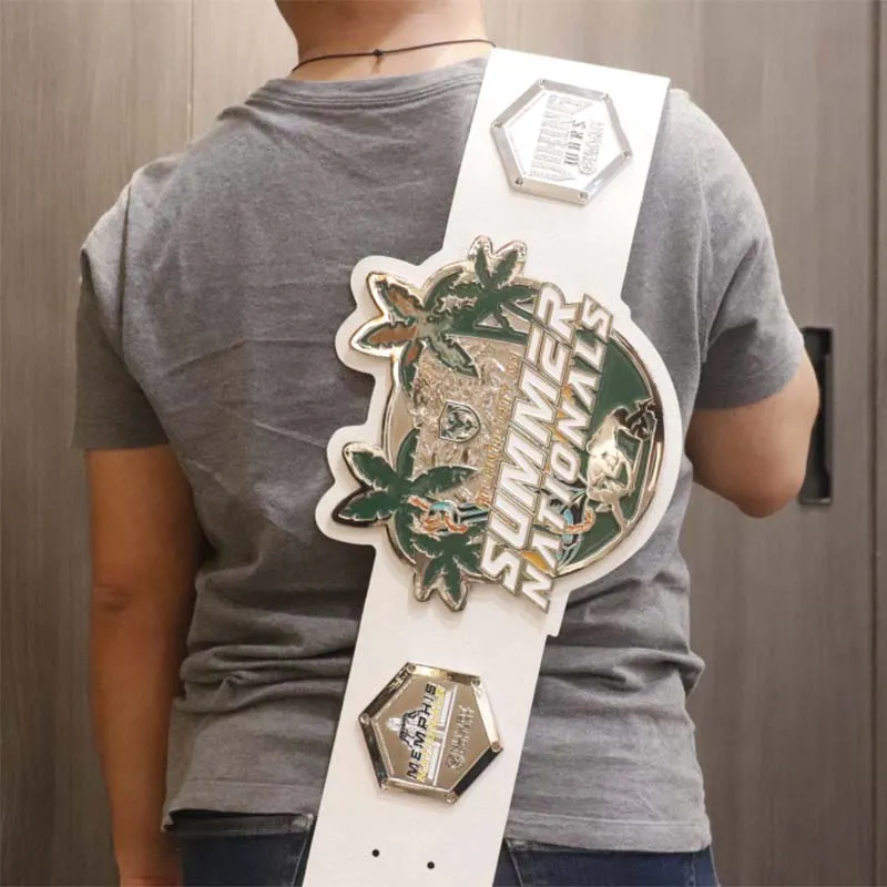 A man stands wearing chanmpionship belt adorned with a colorful sticker, showcasing a unique personal style.