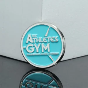 Logo of The Athletes Gym displayed on a blue pin, symbolizing fitness and athletic excellence.