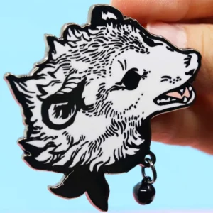 A hand gently holds a black and white hedgehog pin, showcasing its intricate design and charming features.