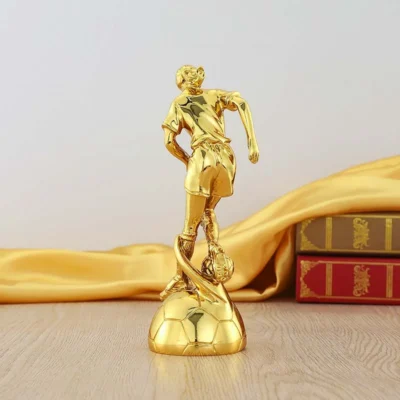 A gold statue of a soccer player elegantly displayed on a table, showcasing intricate details and craftsmanship.