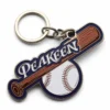 Un portachiavi con mazza da baseball e palla appoggiato su una superficie grigia, che mette in mostra un accessorio giocoso a tema sportivo.