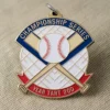 Gros plan sur une médaille en forme de balle de baseball et de batte, sur fond de tissu doux, mettant en valeur son design complexe.
