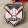 Gros plan sur une médaille en forme de balle de baseball et de batte, sur fond de tissu doux, mettant en valeur son design complexe.