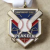 Gros plan sur une médaille en forme de balle de baseball et de batte, sur fond de tissu doux, mettant en valeur son design complexe.