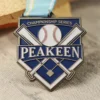 Gros plan sur une médaille en forme de balle de baseball et de batte, sur fond de tissu doux, mettant en valeur son design complexe.