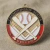 Gros plan sur une médaille en forme de balle de baseball et de batte, sur fond de tissu doux, mettant en valeur son design complexe.
