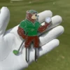 A golf glove featuring a golf ball and bear pin, alongside a golf divot tool for course maintenance.