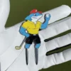 A shark wearing a red hat grips a golf club and a divot tool, combining humor with a love for golf.
