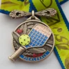 A medal adorned with a pickleball racket and ball, celebrating success in pickleball competitions.