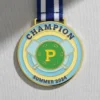 A pickleball medal featuring the word "Champion" prominently displayed on its surface.