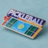 Un pin de pickleball con la palabra "pickleball" bien visible en su superficie.