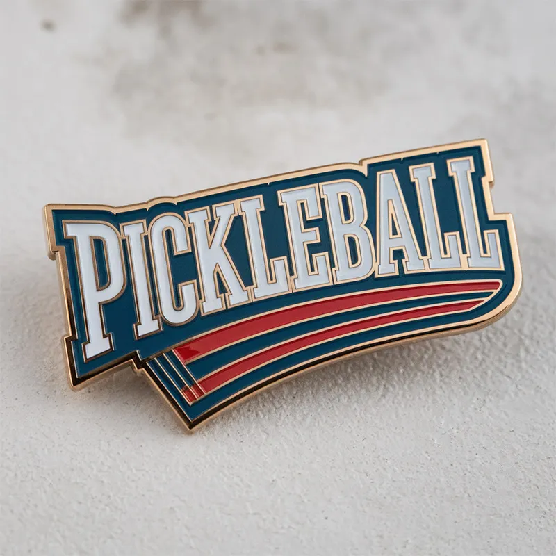 A pickleball pin featuring the word "pickleball" prominently displayed on its surface.