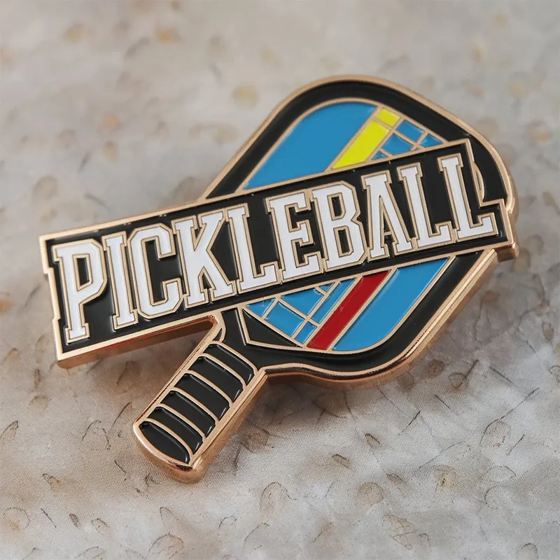 A pickleball pin featuring the word "pickleball" prominently displayed on its surface.