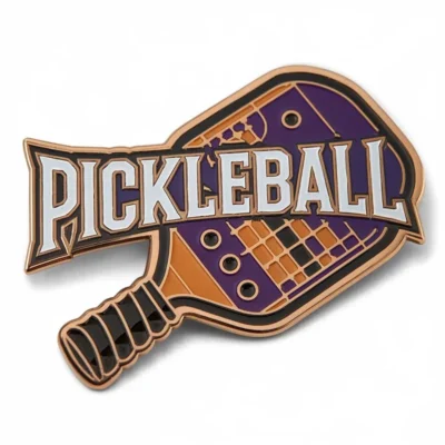 A pickleball pin featuring the word "pickleball" prominently displayed on its surface.