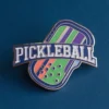 Un pin de pickleball con la palabra "pickleball" bien visible en su superficie.
