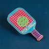 Un pin de pickleball con la palabra "pickleball" bien visible en su superficie.