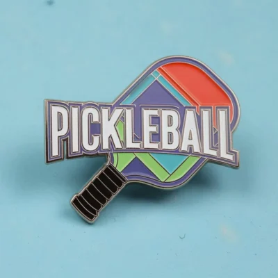 A pickleball pin featuring the word "pickleball" prominently displayed on its surface.