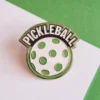 Un pin de pickleball con la palabra "pickleball" bien visible en su superficie.