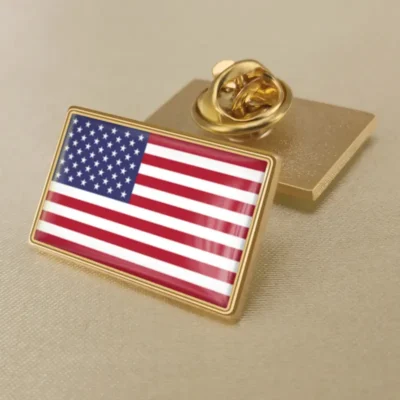 A gold pin featuring the United States flag, symbolizing patriotism and national pride.