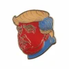 Eine Anstecknadel mit einem Bild von Donald Trump, das seine ikonische Frisur und seinen Ausdruck zeigt.