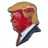 Eine Anstecknadel mit einem Bild von Donald Trump, das seine ikonische Frisur und seinen Ausdruck zeigt.
