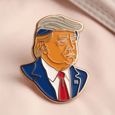 Un badge à épingles représentant Donald Trump, avec sa coiffure et son expression emblématiques.