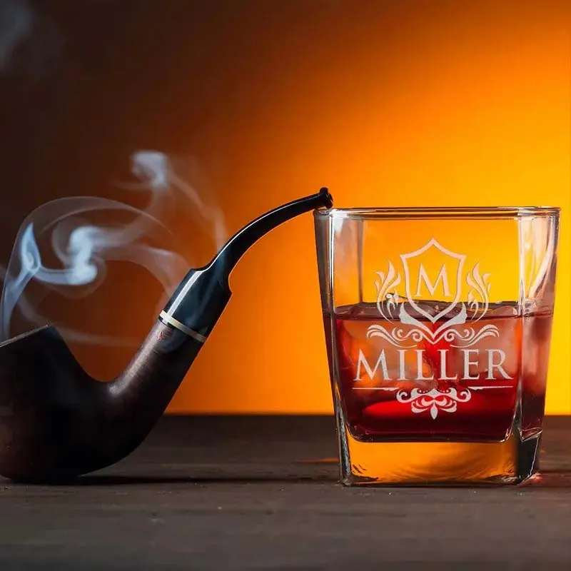 A glass of whiskey beside a classic pipe, showcasing a refined drinking experience.