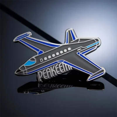 An airplane-shaped pin displaying the word "peaken" prominently.