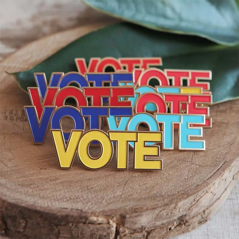 A collection of custom vote pin badges featuring the word "vote" prominently displayed on each pin.