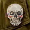 Spilla personalizzata con teschio d'oro e occhi neri, che rappresenta un accessorio unico ed elegante per qualsiasi abbigliamento.
