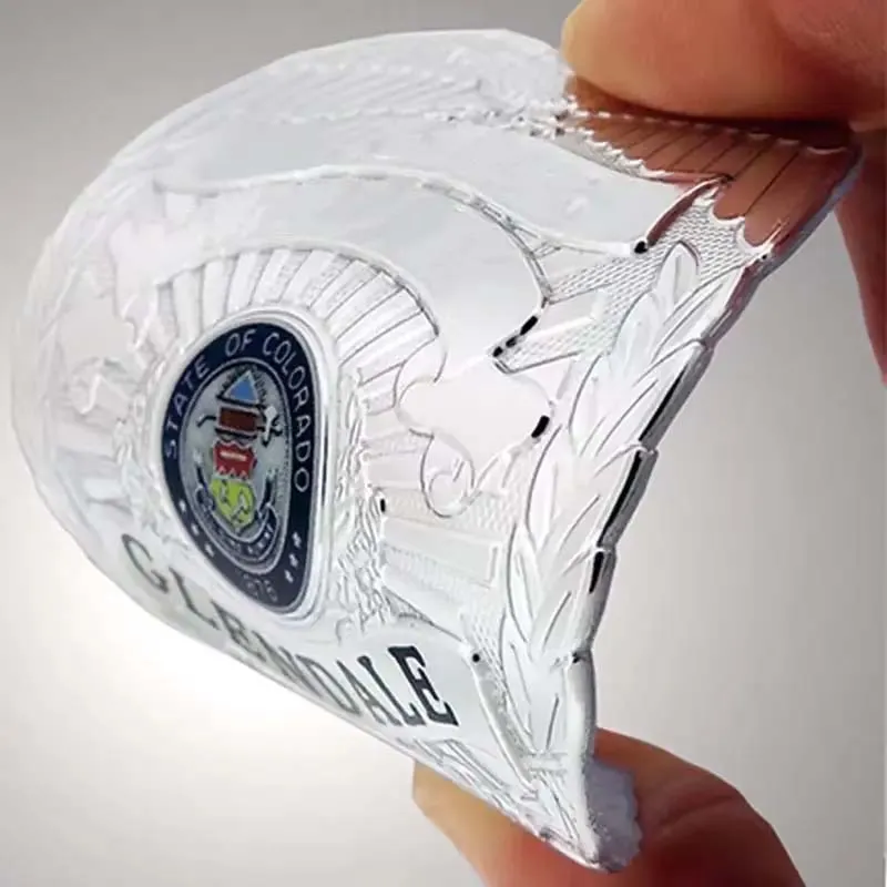 A person proudly displays a custom flexible TPU police badge, showcasing its silver color and distinctive shape.