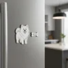 A white dog magnet attached to a refrigerator in a kitchen, adding a playful touch to the home decor.