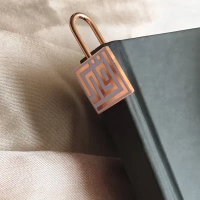 A book secured with a padlock, featuring custom Islamic bookmarks beside it, symbolizing knowledge and protection.