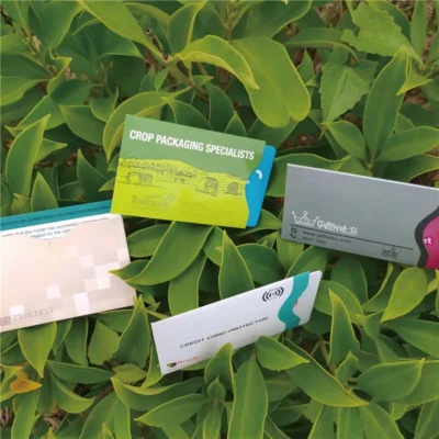 Four business cards placed on vibrant green leaves, showcasing a custom RFID blocking sleeve for added security.