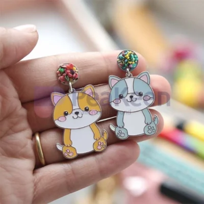 A person showcasing custom soft enamel earrings featuring a playful cat design.