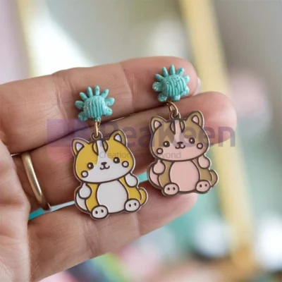 A person showcasing custom soft enamel earrings featuring a playful cat design.