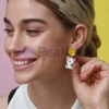 Une personne présentant des boucles d'oreilles en émail souple personnalisées, ornées d'un chat enjoué.