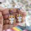 Une personne présentant des boucles d'oreilles en émail souple personnalisées, ornées d'un chat enjoué.