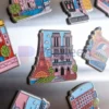 Un vibrante surtido de imanes de nevera personalizados para viajes que muestran diversos diseños de ciudades y lugares emblemáticos.