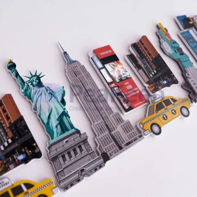 A collection of custom travel fridge magnets featuring the Statue of Liberty, a taxi, and a bus.