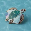 Un chapeau vert orné d'une épingle à tortue personnalisée, un accessoire unique et ludique.