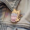 Un gatto ornato da una spilla smaltata personalizzata con bubble tea, che mette in mostra un accessorio giocoso e di tendenza.