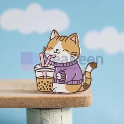 A cozy cat in a sweater holds a cup of bubble tea, showcasing custom boba cat pins in a playful setting.