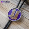 Corbata bolo metálica personalizada con un pasador de bota vaquera morado y dorado en un elegante cordón negro.