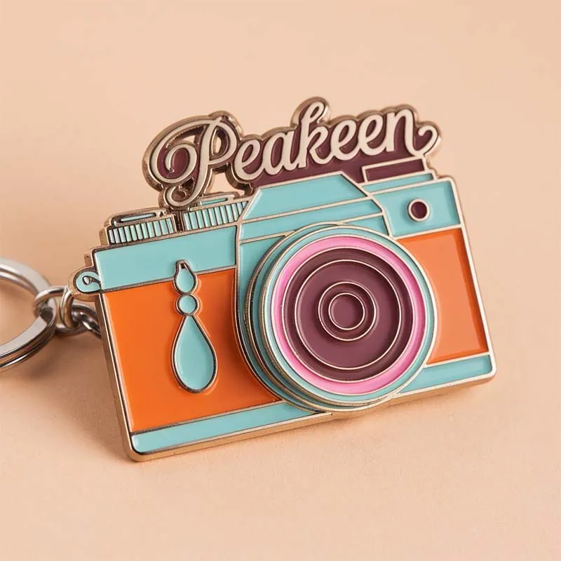 Custom camera keychain featuring the word "peakeen" elegantly displayed on a stylish design.