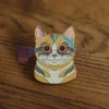 Una vivace spilla a forma di gatto con il disegno di un volto artistico e colorato, perfetta per dare un tocco di classe a qualsiasi collezione di accessori.