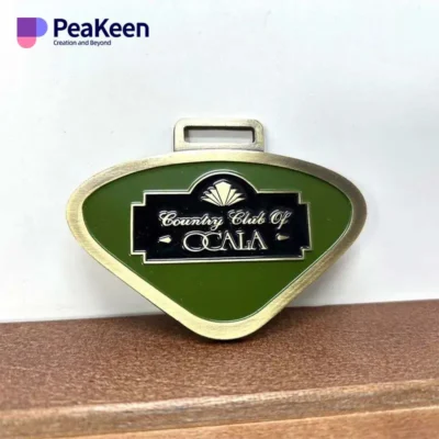 Green and gold metal key chain featuring "Beauty World of Ocala," designed as a golf bag tag.